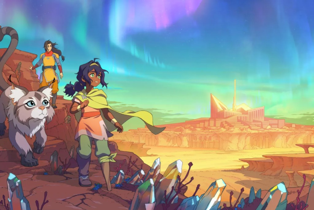 Two animated characters and a half-cat, half-lemur creature traverse a rocky desert landscape under a vibrant aurora-lit sky, with a distant city in the background.